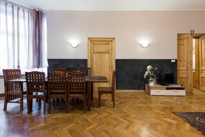 Un coin repas avec une table et des chaises en bois, une porte en bois et un téléviseur posé sur un meuble.