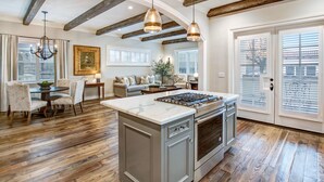 A spacious kitchen with a central island, wooden beams on the ceiling, and a dining area with a round table and chairs. - Brand New 2 Bedroom Master Suites with Chefs Kitchen Steps to Sonoma Plaza (Sonoma)