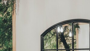 Une chambre à coucher avec un miroir incurvé qui reflète un lit et un arbre à l’extérieur.