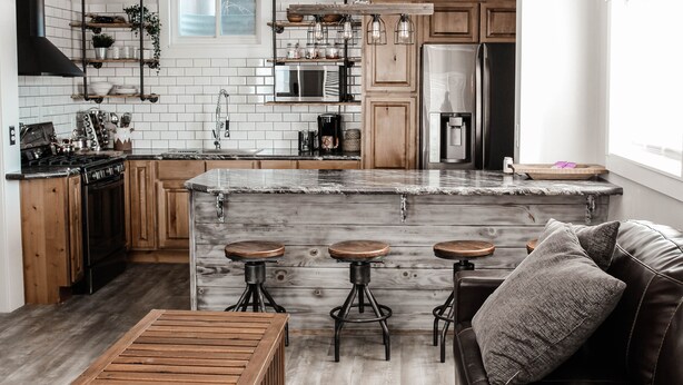 Une cuisine moderne dotée d’un îlot central, de tabourets de bar et d’une table à manger en bois.