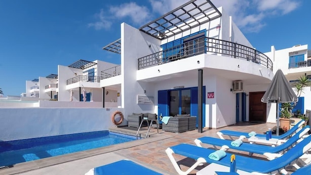 Ein modernes Hotel mit Pool, Liegestühlen und einem überdachten Außenbereich.
