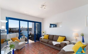 Una sala de estar moderna con sofá, sillones, una mesita de centro y un balcón con vistas.