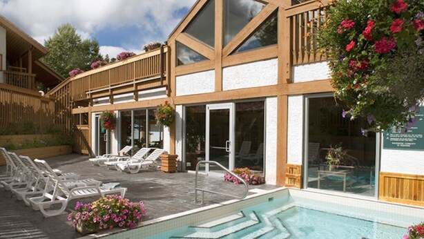 A modern hotel with a pool area, sun loungers, and a wooden deck. - Spacious two-bedroom fully outfitted condo in Banff (Banff)