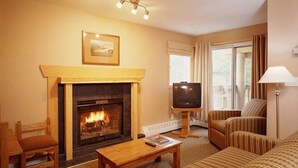 A cozy living room with a fireplace, a television, and comfortable seating. - Spacious two-bedroom fully outfitted condo in Banff (Banff)