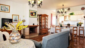 A living room with a fireplace, a dining area, and a kitchen. - Villa Pastor, Torrox, Málaga. (Torrox)