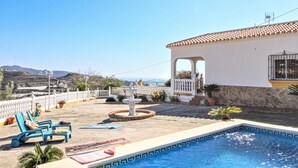 A pool area with lounge chairs, a fountain, and a view of the sea. - Villa Pastor, Torrox, Málaga. (Torrox)