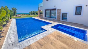 Une maison moderne dotée d’une grande piscine, d’une pelouse bien entretenue et offrant une vue sur l’océan.