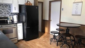 A compact kitchen with a refrigerator, stove, and a small dining area with stools. - Nice 3 Bed Apt near Downtown Boston (Revere)