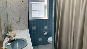 A bathroom with a blue tiled wall, a white sink with a mirror, a window, and a shower curtain. - Nice 3 Bed Apt near Downtown Boston (Revere)