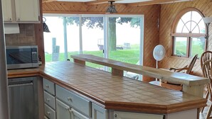 A kitchen with a central island, white cabinets, a microwave, and a dishwasher. - Lake Huron Beach  (Fort Gratiot Twp)