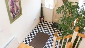 Un escalier avec un sol à carreaux, un radiateur, un tableau encadré et une plante.