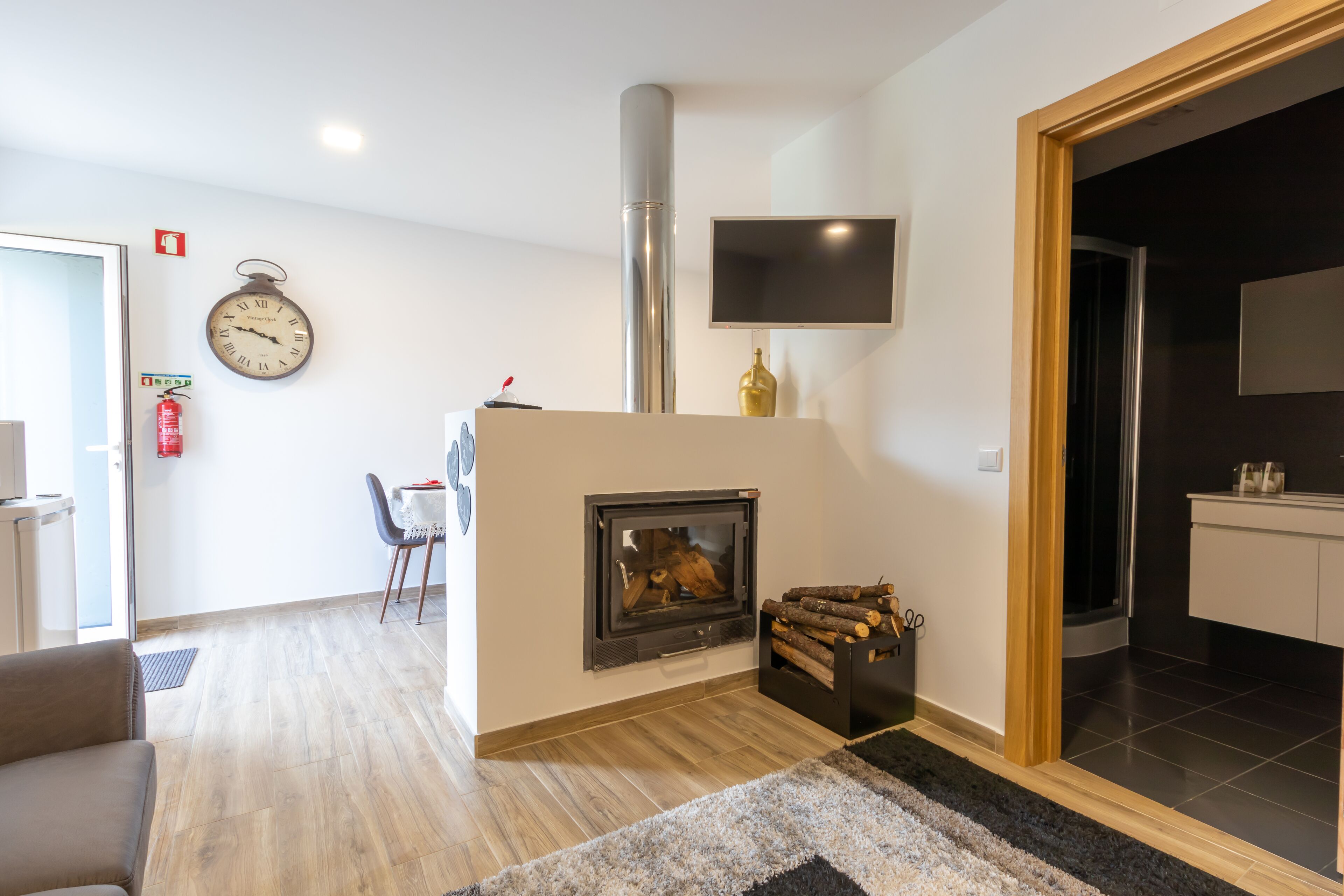 Una sala de estar moderna con chimenea, un reloj y un televisor de pantalla plana montado en la pared.