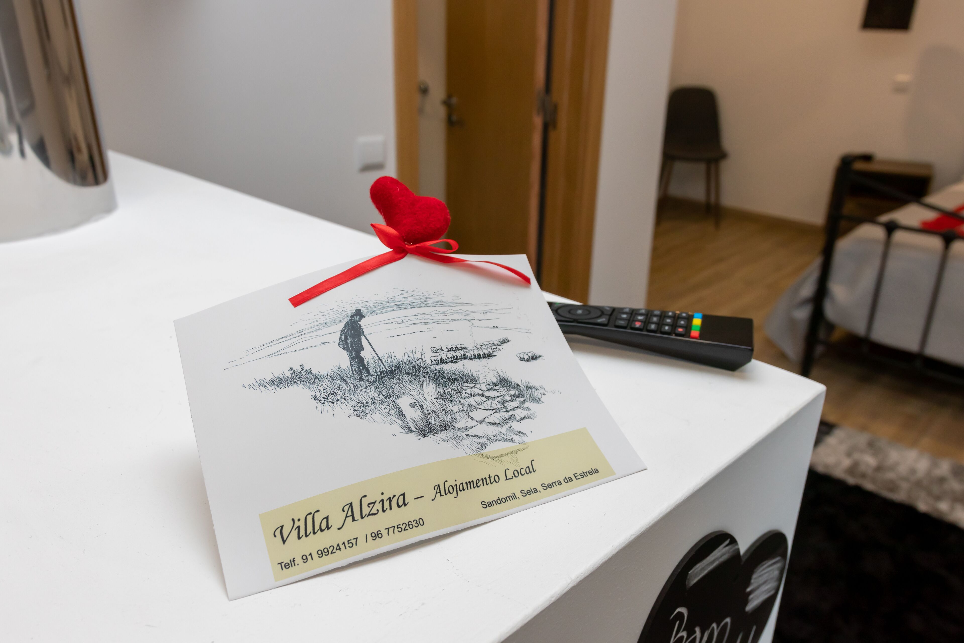 A white box with a remote control and a card on top. The card has a drawing and text.