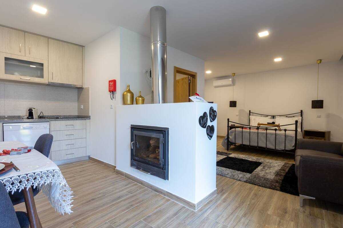 A modern kitchen with a built-in stove, a dining area with a table and chairs, and a living room with a sofa and a bed.