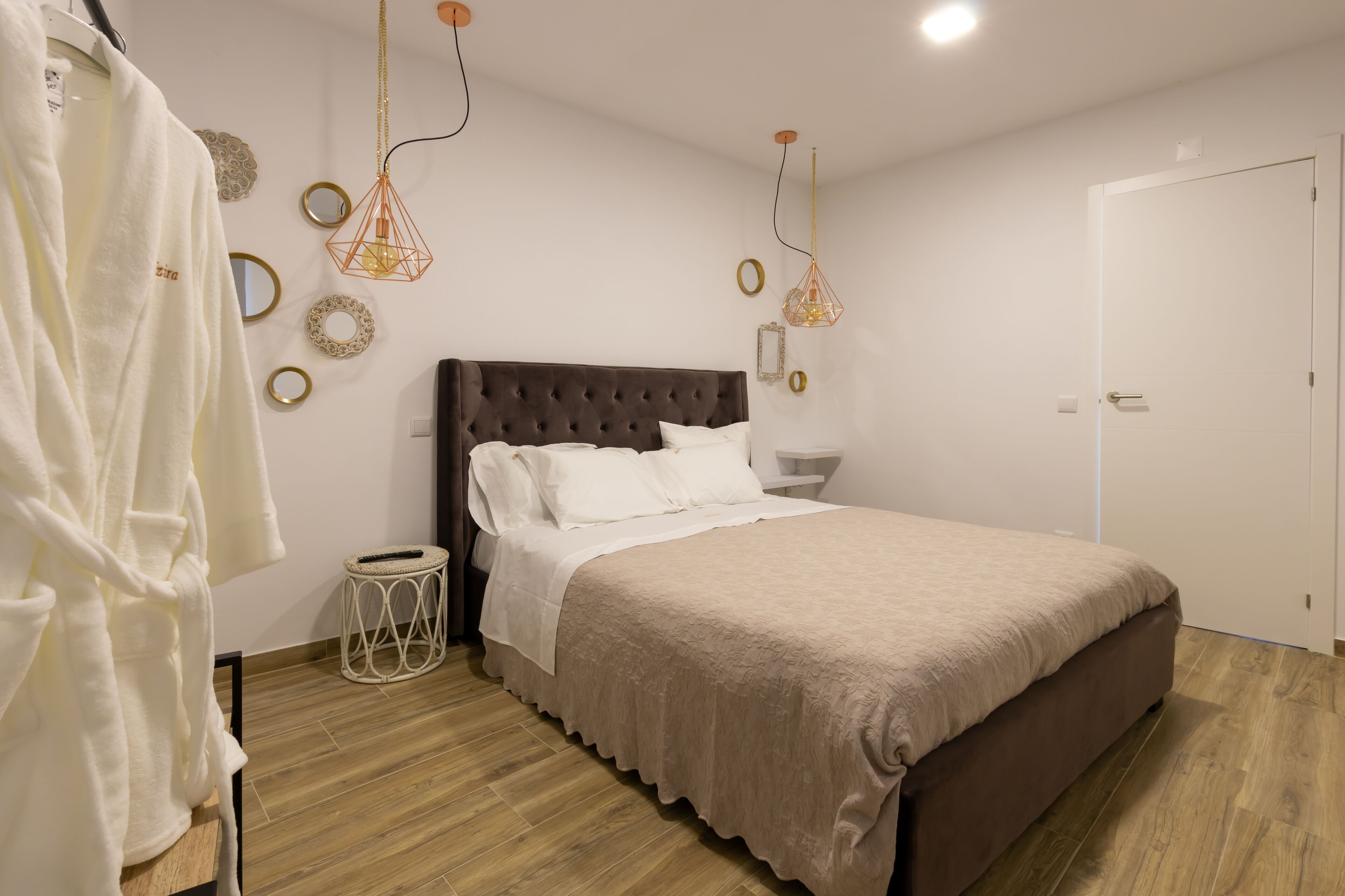 Ein Schlafzimmer mit einem großen Bett, einem Nachttisch, einer Hängelampe und einer Tür.