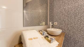 Un baño con lavamanos blanco, un espejo y una toalla con la inscripción 'Villa Azira'.