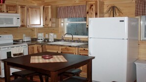 A wooden cabin-style kitchen with a stove, microwave, sink, and refrigerator. - Hocking hills backwoods retreat -Whispering Winds (Rockbridge)