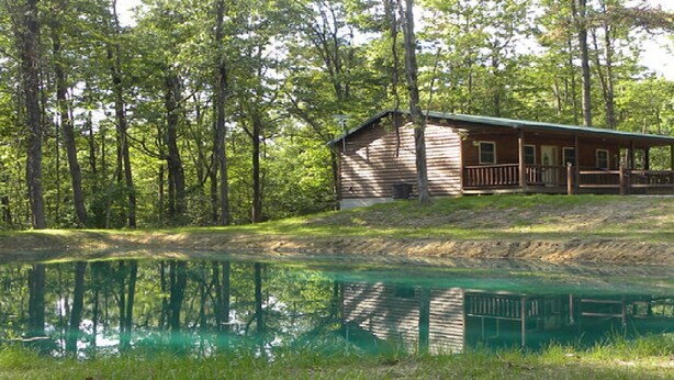 A cabin with a porch, surrounded by trees and a pond. - Hocking hills backwoods retreat -Whispering Winds (Rockbridge)