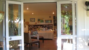 Un umbral abierto que da a una sala de estar con un sofá, un sillón y una estantería.