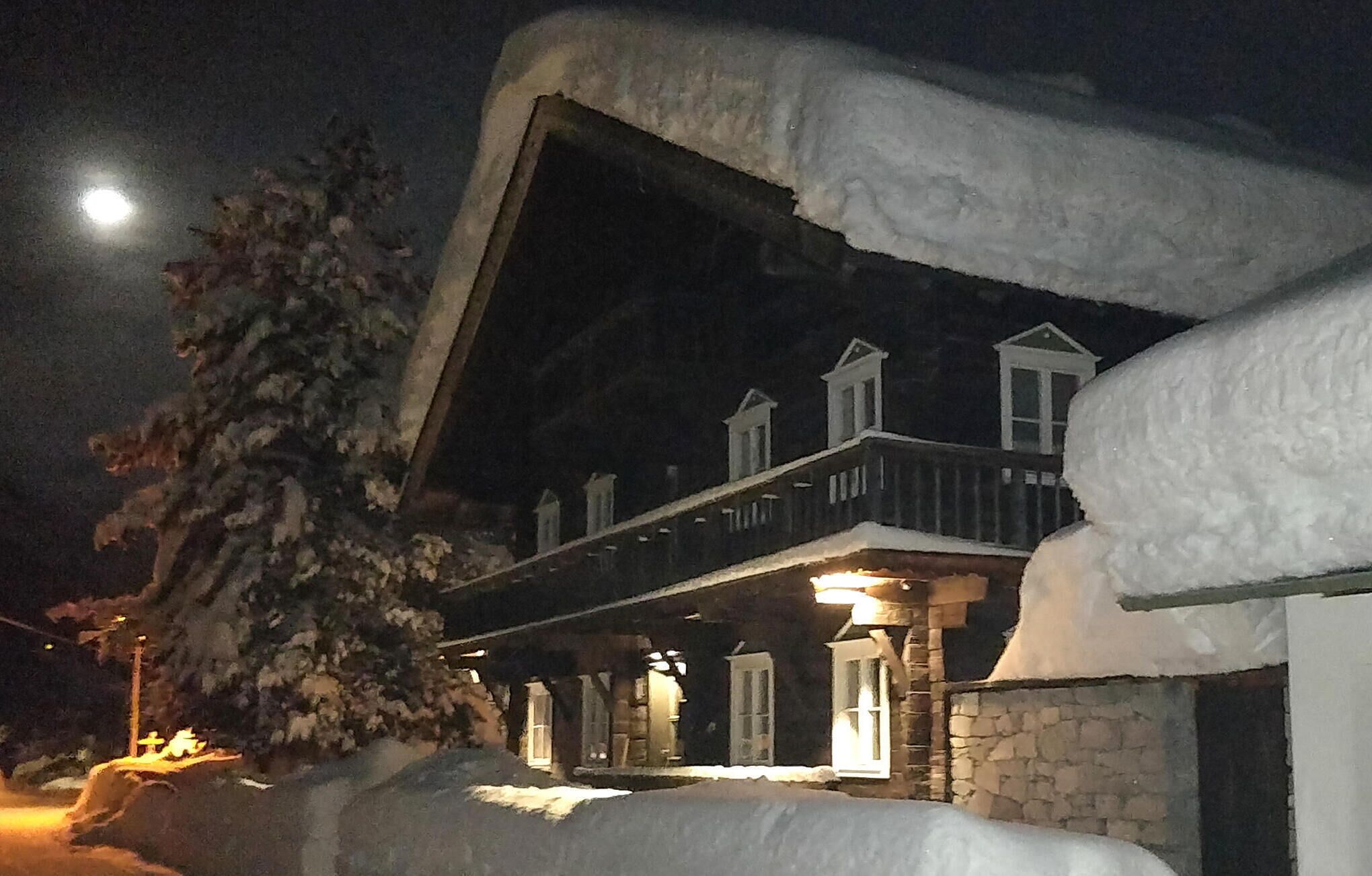 Un bâtiment enneigé, doté d’un balcon et d’une entrée illuminée.