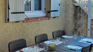 Ulkoterassi, jossa on kuudelle henkilölle katettu ruokapöytä ja sen ympärillä tuoleja.
