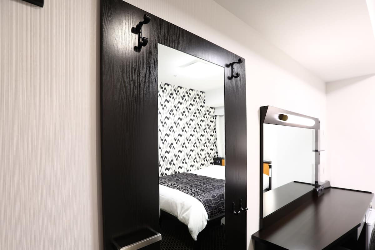 Een hotelkamer met een bed, een bureau, een spiegel en een kledingkast.