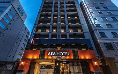 A modern hotel building with a prominent sign for APA HOTEL.