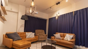 A modern living room with two brown leather sofas, a glass coffee table, and a large window with dark curtains. - Core Resort House 2 In Ishigaki (Ishigaki)