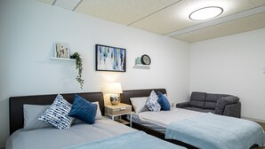 A hotel room with two beds, a gray sofa, a wall-mounted clock, and a framed abstract painting. - Core Resort House 2 In Ishigaki (Ishigaki)