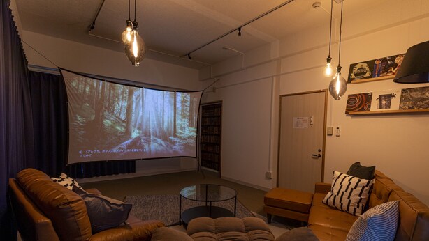 A cozy living room with a large screen, leather sofas, and a coffee table. - Core Resort House 2 In Ishigaki (Ishigaki)