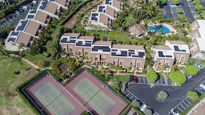 Eine Vogelperspektive eines Wohnkomplexes mit mehreren Gebäuden, einem Tennisplatz und einem Parkbereich.
