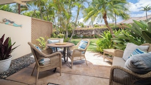 Ein Patio mit Korbmöbeln, einem runden Tisch und einem Blumentopf.
