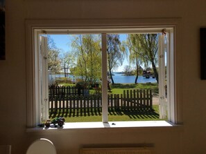 A room with a large window overlooking a lake, a wooden fence, and a small toy car on the windowsill.