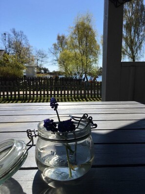 A glass jar with flowers on a wooden table.