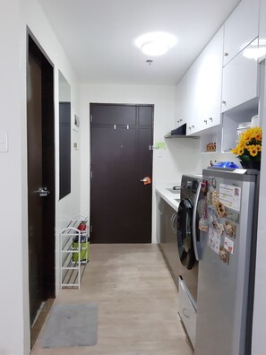 Compact kitchen area with a refrigerator, cabinets, and laundry facilities.