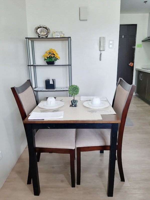 Enjoy meals in this cozy dining area with a table for two, comfortable chairs, and a stylish shelf above.