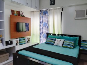 Cozy retreat with a comfortable bed, TV, and stylish shelving.