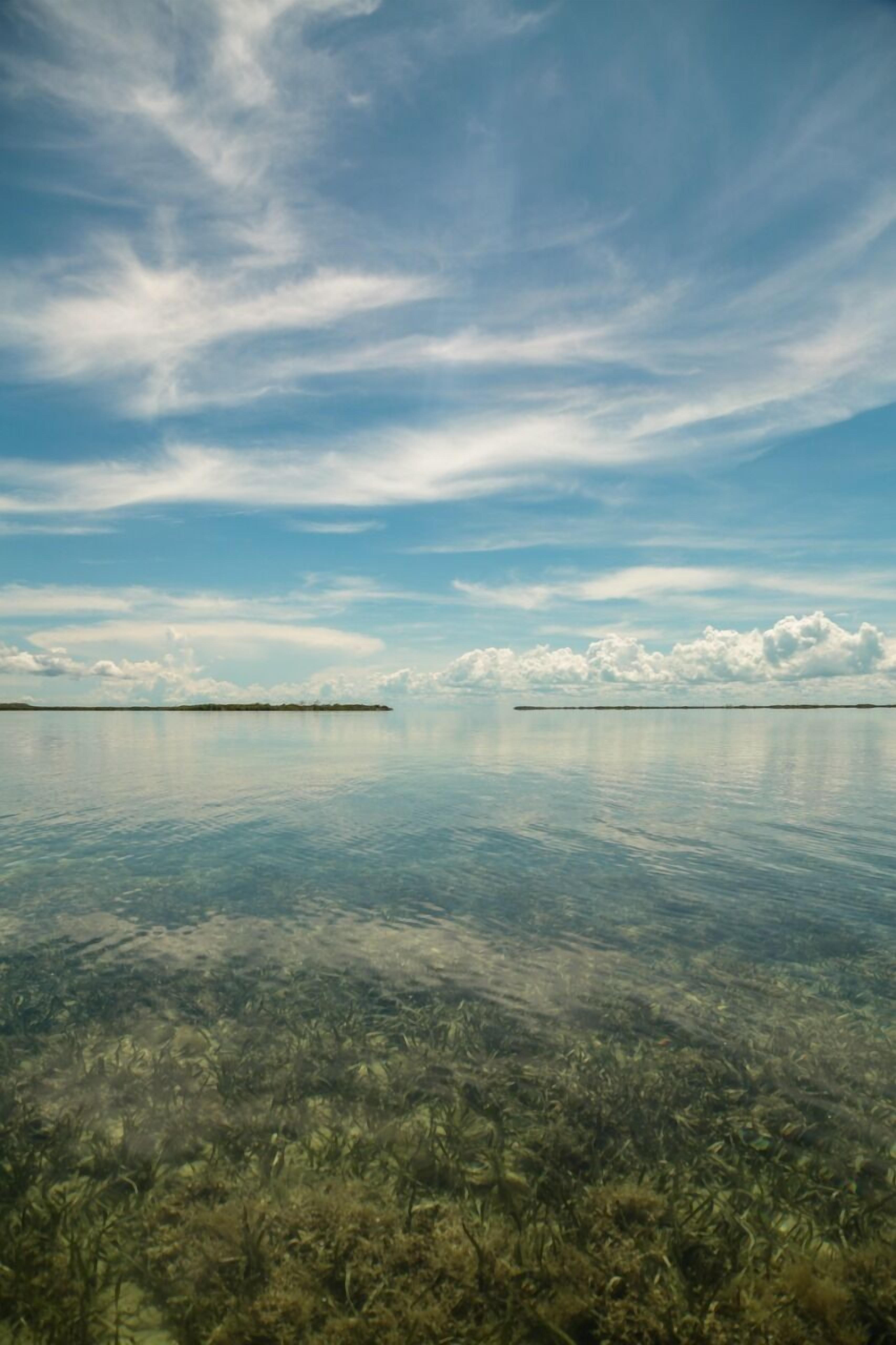 On aperçoit clairement une étendue d’eau calme, avec une rive lointaine et un ciel dégagé.