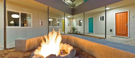 A fire pit in a courtyard with a modern building in the background.