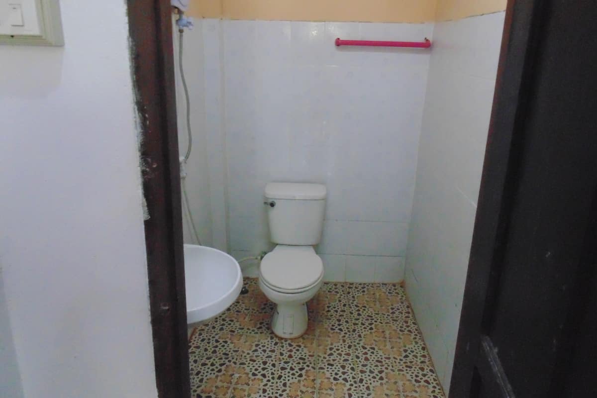 Une petite salle de bain avec des toilettes, un lavabo et un sol carrelé.