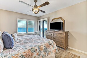 Une chambre à coucher avec un lit, un ventilateur de plafond, une commode et un téléviseur.