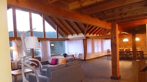 Un amplio salón con un sofá, una escultura decorativa de astas y una zona de comedor con sillas y mesas.