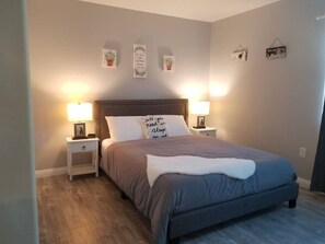 Ein Schlafzimmer mit einem großen Bett, zwei Nachttischen mit Lampen und dekorativer Wandgestaltung.