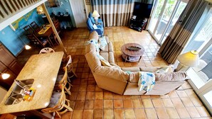 Uma sala de estar ampla, com um sofá grande, uma mesa de jantar e uma televisão.