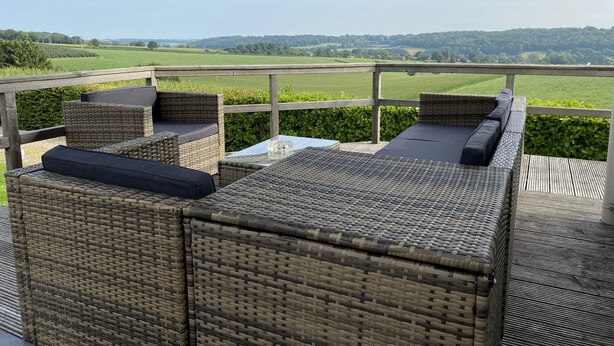 A wicker outdoor seating area with a view of a green landscape.