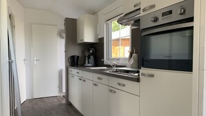 A modern kitchen with white cabinets, a built-in oven, a coffee maker, and a window with a view of the outside.
