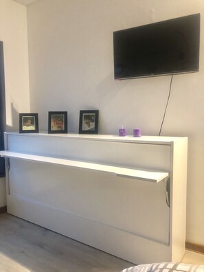 A room with a white console table, a flat-screen TV mounted on the wall, and three framed pictures on the table. - Department View to the Obelisk, reception and security 24 hours (C1043AAV)