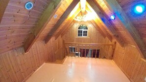 A wooden attic room with a sloped ceiling, a window, and a staircase leading to a lower level. - Yangsan Park Pension (Yangsan)