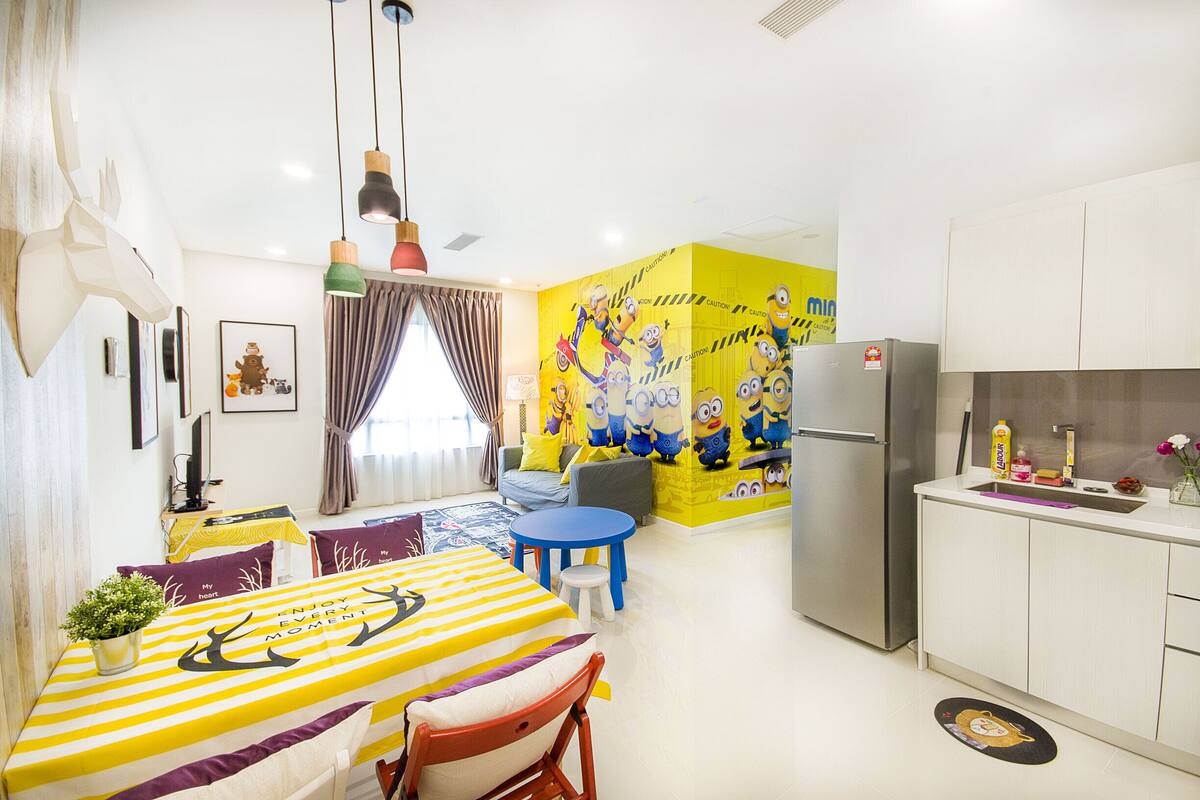 A modern kitchen with a refrigerator, a sink, and a dining area with a yellow-striped table and chairs.