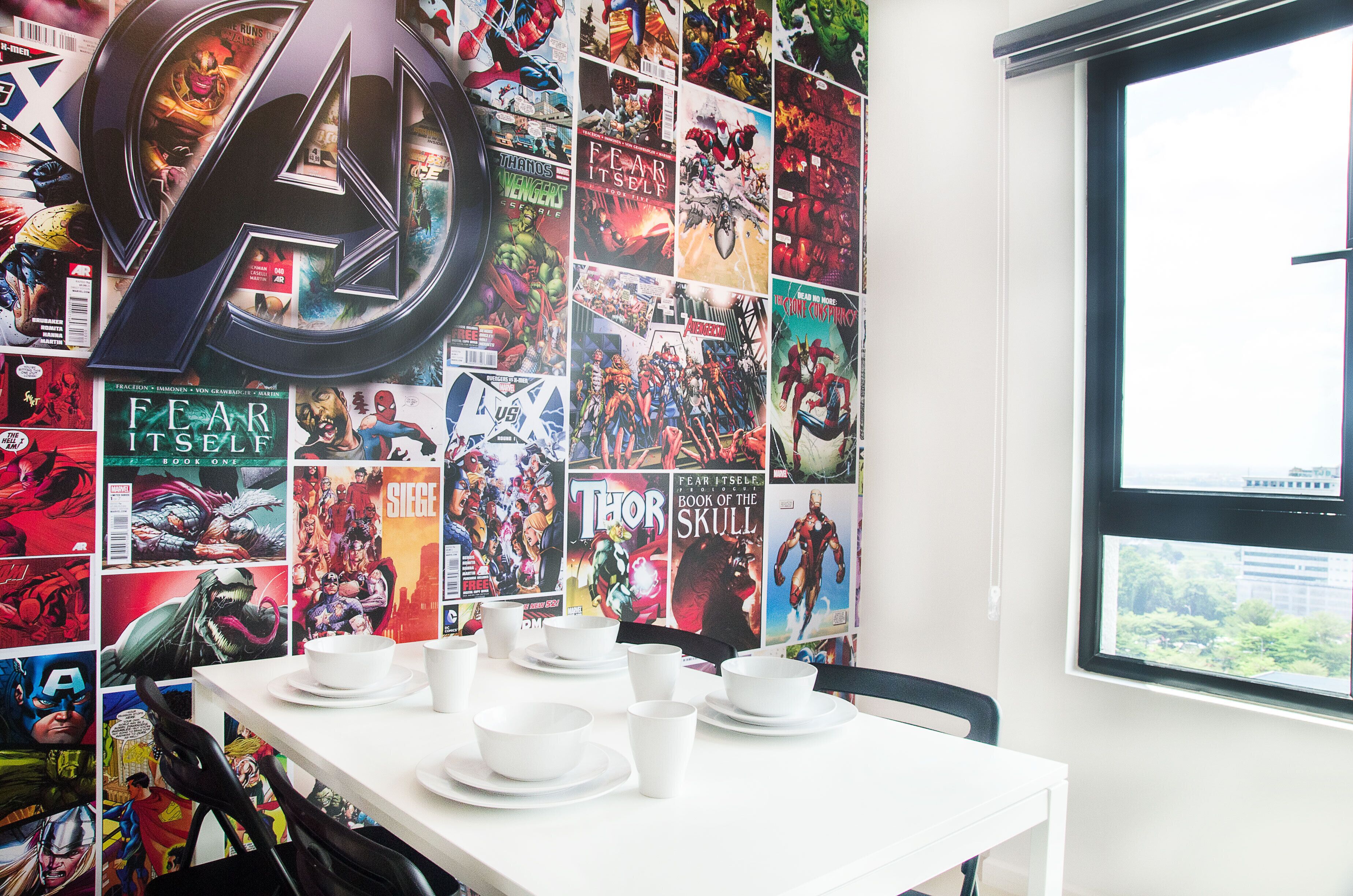 A room with a wall covered in comic book posters, a large arrow decoration, and a table with white dishes.
